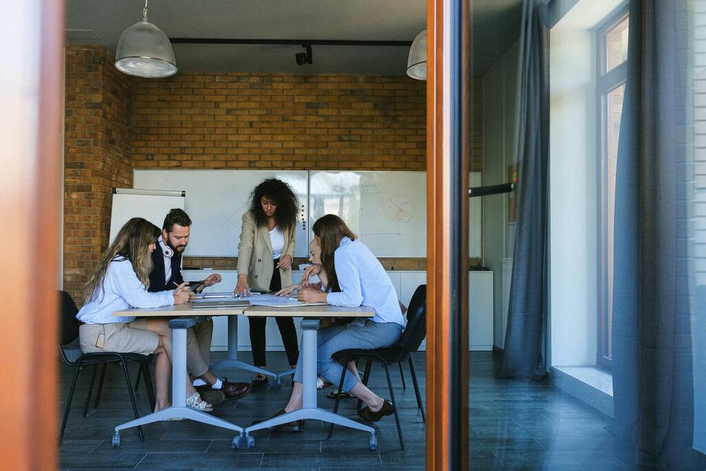 IT team collaborating and planning at a desk with whiteboards, highlighting teamwork and project management.